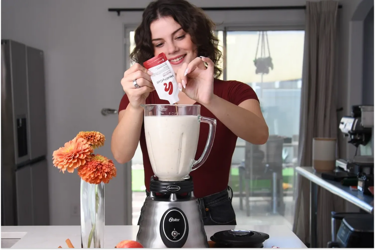Woman mixing HealthyCell Glucose Support Berberine supplement into a morning shake using a blender in a modern kitchen for her weight loss journey.