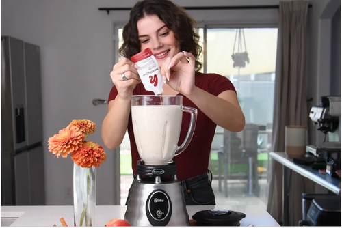Woman mixing HealthyCell Glucose Support Berberine supplement into a morning shake using a blender in a modern kitchen for her weight loss journey.