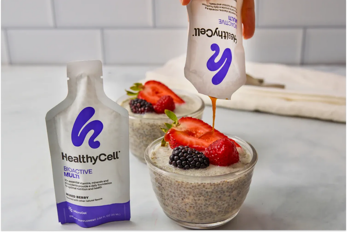 A bowl of snack with yogurt,chia seeds, grapes, strawberry and a Healthy Cell BioActive Multi