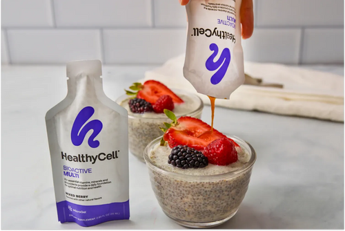 A bowl of snack with yogurt,chia seeds, grapes, strawberry and a Healthy Cell BioActive Multi
