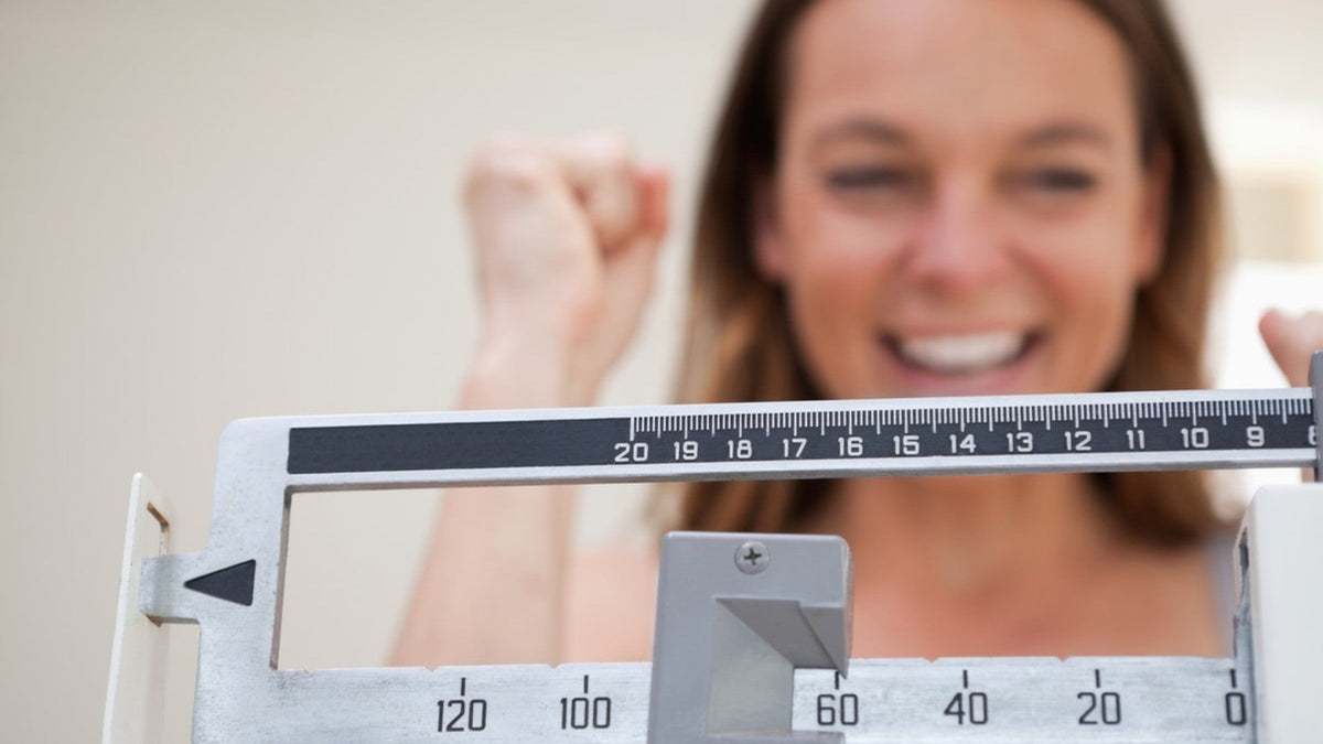 female on scale looking for weight loss goal